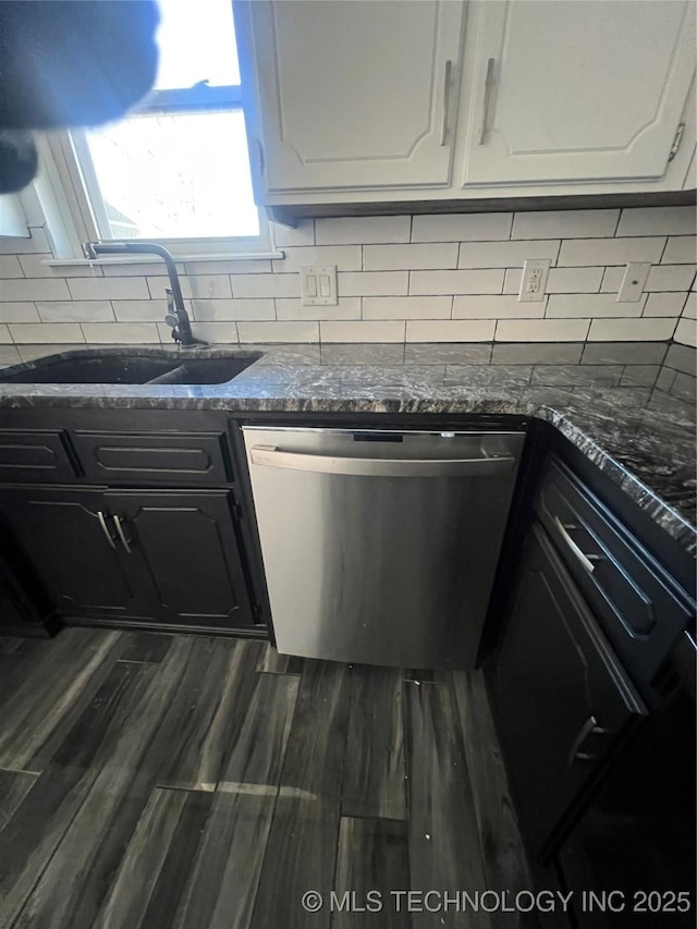 kitchen with white cabinetry, dark hardwood / wood-style flooring, dark stone countertops, stainless steel dishwasher, and sink