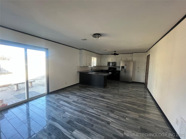 kitchen with appliances with stainless steel finishes, dark wood-type flooring, white cabinetry, decorative backsplash, and kitchen peninsula