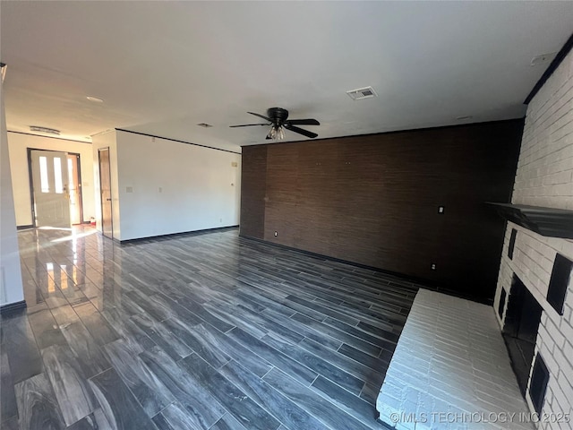 unfurnished living room featuring ceiling fan and a fireplace