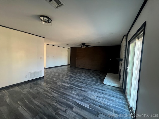 empty room featuring ceiling fan, dark hardwood / wood-style flooring, and a brick fireplace