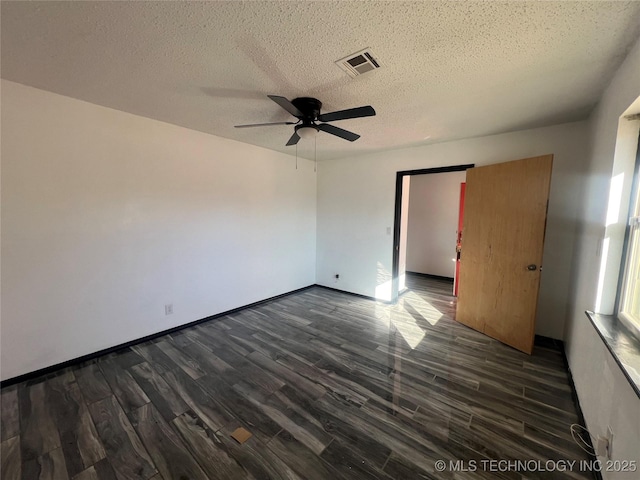 empty room featuring ceiling fan, dark wood-type flooring, and a textured ceiling