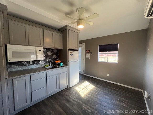 kitchen with white appliances, decorative backsplash, sink, a wall unit AC, and gray cabinetry