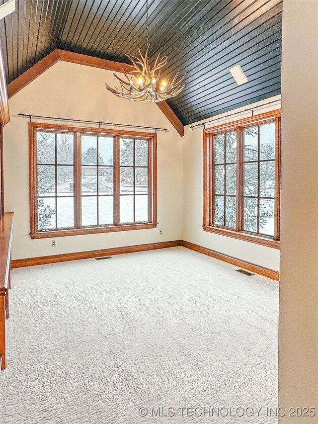 unfurnished room with plenty of natural light, carpet, and a notable chandelier