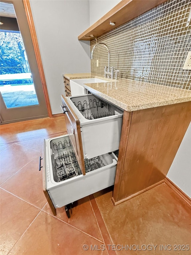 kitchen with sink, backsplash, light stone counters, and light tile patterned floors