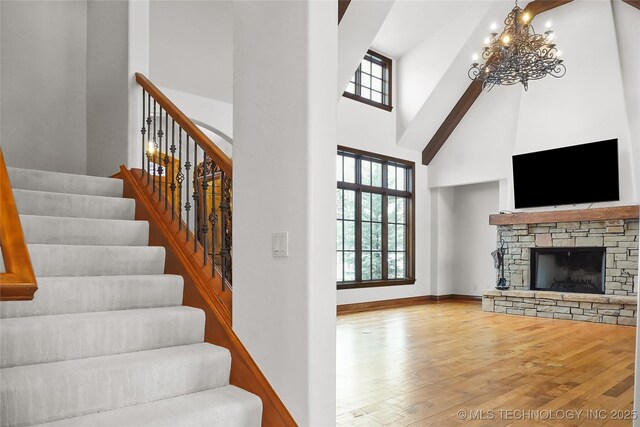 living room with a fireplace, light hardwood / wood-style floors, a towering ceiling, and a notable chandelier