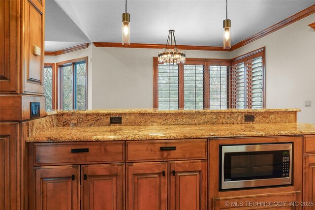 kitchen featuring decorative light fixtures, light stone counters, and crown molding