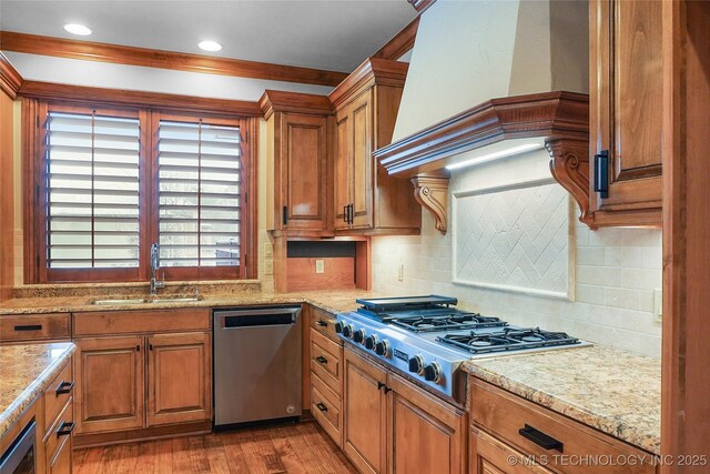 kitchen featuring custom exhaust hood, light hardwood / wood-style floors, appliances with stainless steel finishes, tasteful backsplash, and sink