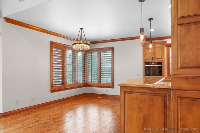 kitchen with light wood-type flooring, pendant lighting, oven, and ornamental molding