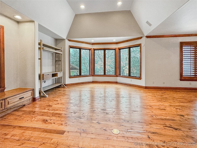 unfurnished living room with vaulted ceiling, a wealth of natural light, and light hardwood / wood-style flooring