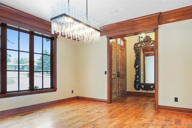 unfurnished room with light hardwood / wood-style floors and a chandelier