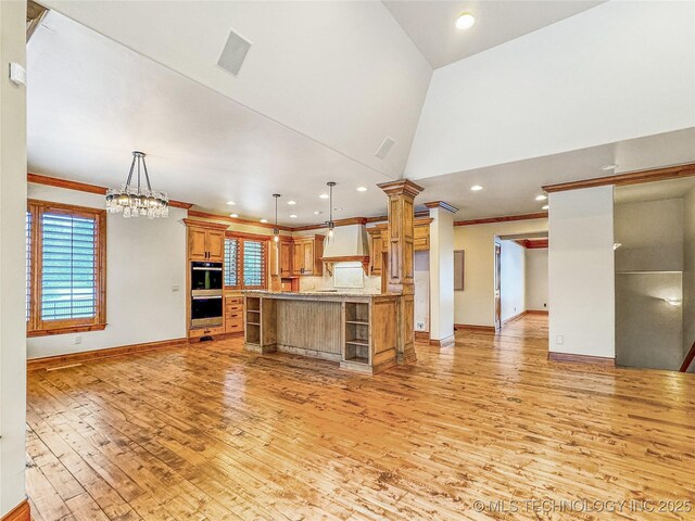 kitchen with vaulted ceiling, decorative light fixtures, premium range hood, a kitchen island, and decorative columns