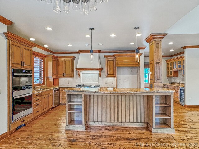 kitchen with a center island, tasteful backsplash, custom range hood, stainless steel double oven, and decorative light fixtures