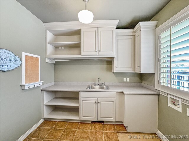 kitchen with sink, white cabinets, decorative light fixtures, and light tile patterned floors