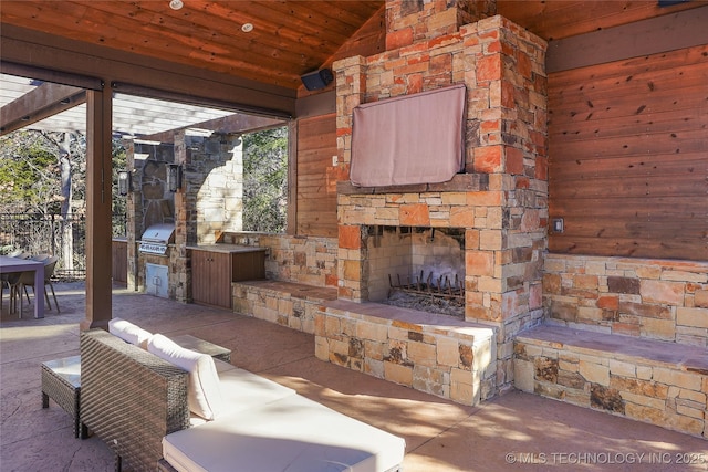 view of patio featuring area for grilling, an outdoor stone fireplace, and a grill