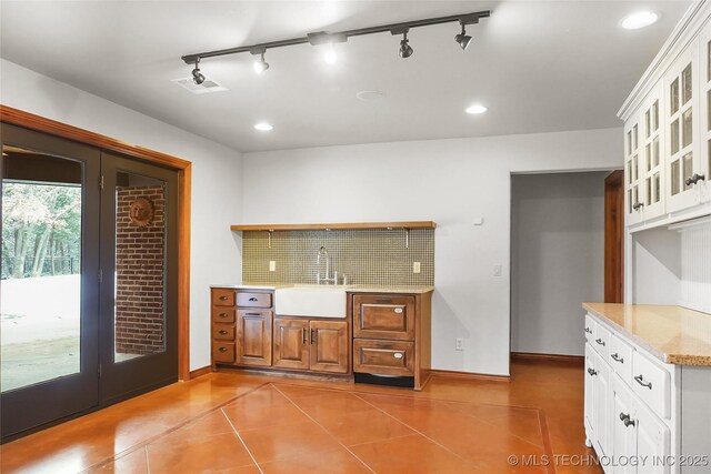 kitchen with sink, rail lighting, white cabinets, and light tile patterned floors