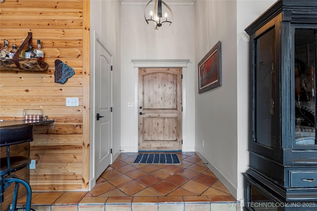 doorway featuring an inviting chandelier, tile patterned floors, and wooden walls