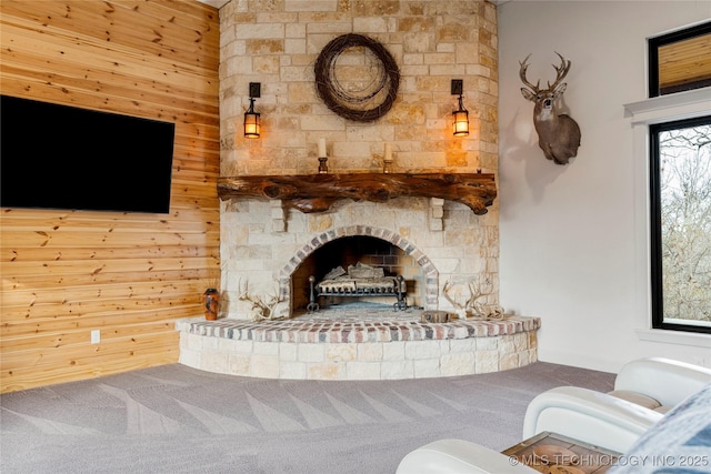 unfurnished living room with a fireplace, carpet floors, and wooden walls