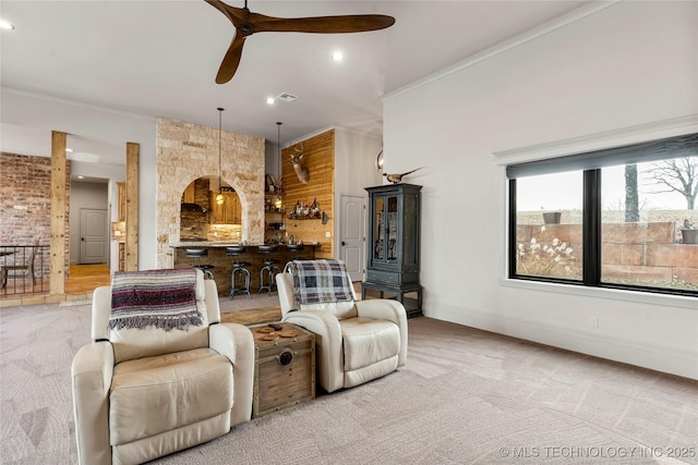 carpeted living room featuring ceiling fan, wood walls, and ornamental molding