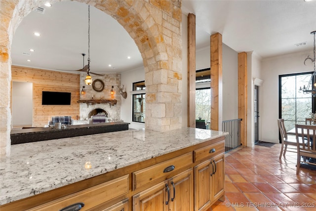 kitchen with decorative light fixtures, a healthy amount of sunlight, a fireplace, and light stone counters