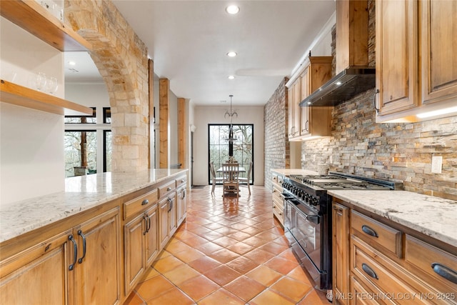 kitchen featuring pendant lighting, double oven range, wall chimney range hood, and a healthy amount of sunlight