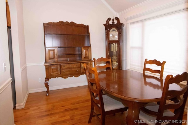 dining space featuring crown molding, lofted ceiling, and light hardwood / wood-style flooring