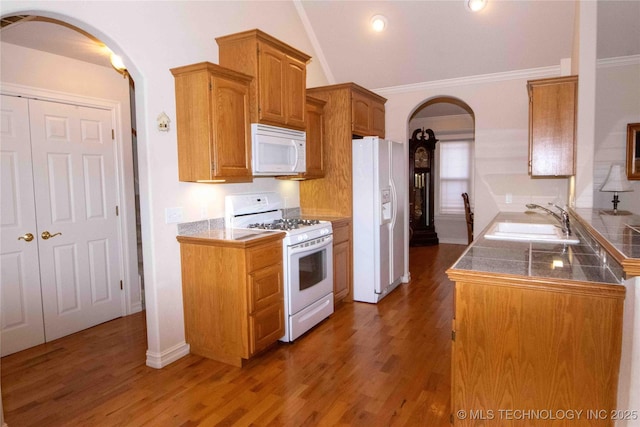 kitchen featuring dark wood-type flooring, sink, crown molding, vaulted ceiling, and white appliances