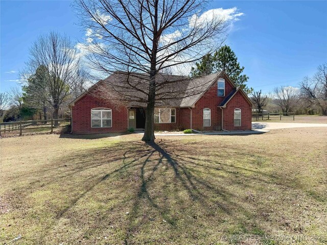 view of front of home featuring brick siding, a front yard, and fence