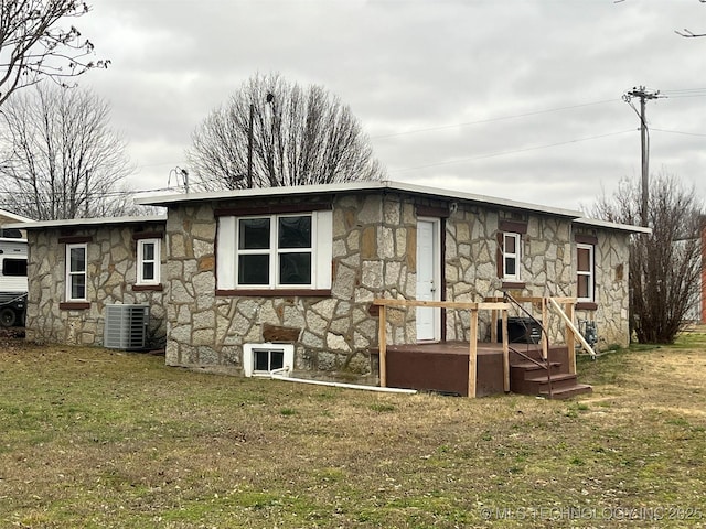 back of property featuring central AC unit and a yard