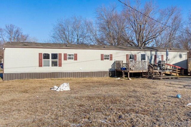 back of property with a wooden deck and a yard