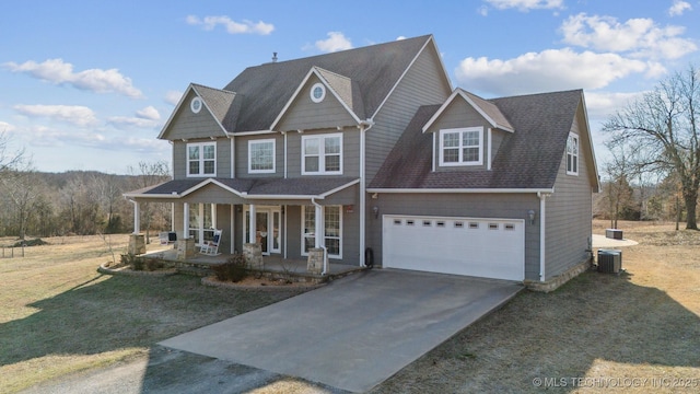 view of front of house with a porch, a garage, cooling unit, and a front lawn