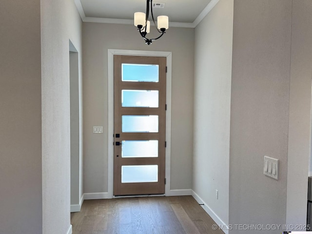 entryway with a chandelier, crown molding, baseboards, and wood finished floors