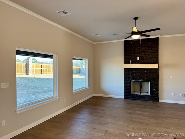 unfurnished living room featuring wood finished floors, visible vents, baseboards, ornamental molding, and a brick fireplace