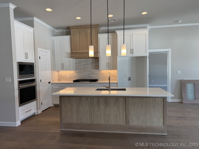 kitchen with light countertops, appliances with stainless steel finishes, a sink, and crown molding