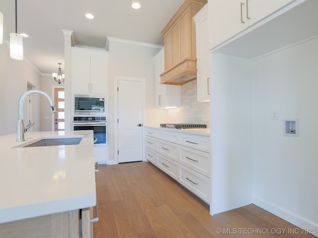 kitchen with crown molding, tasteful backsplash, wood finished floors, a sink, and stainless steel appliances