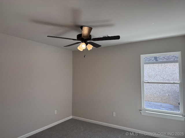 spare room featuring a ceiling fan, dark colored carpet, a healthy amount of sunlight, and baseboards