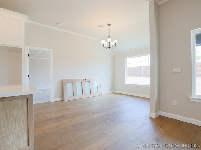 unfurnished dining area with crown molding, baseboards, light wood-style flooring, and a notable chandelier