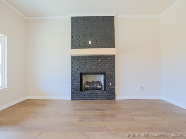unfurnished living room with a brick fireplace, baseboards, ornamental molding, and wood finished floors
