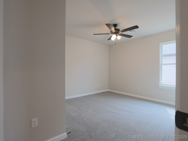 empty room with carpet floors, a ceiling fan, baseboards, and visible vents