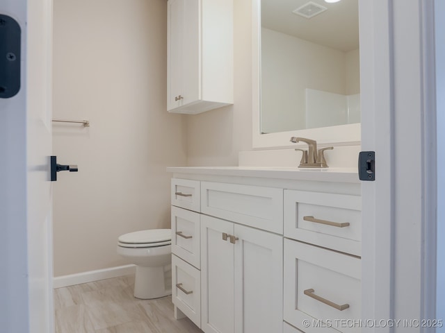bathroom featuring vanity, baseboards, toilet, and visible vents