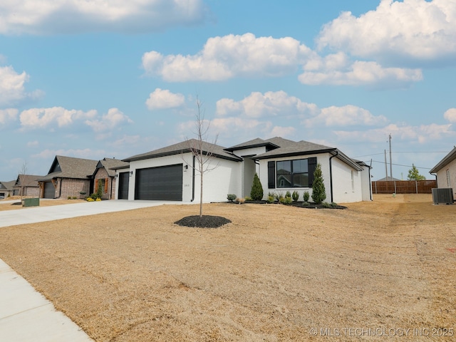 prairie-style house with concrete driveway, a garage, fence, and cooling unit