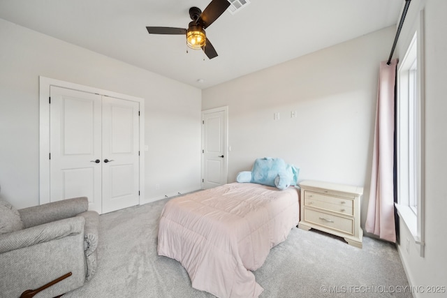 carpeted bedroom with ceiling fan, multiple windows, and a closet