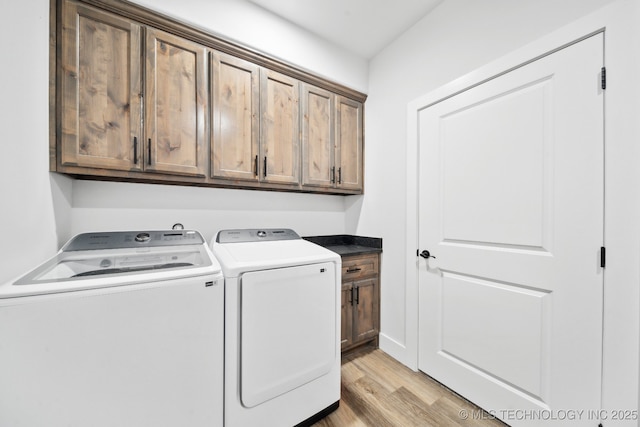 washroom featuring light wood-type flooring, independent washer and dryer, and cabinets