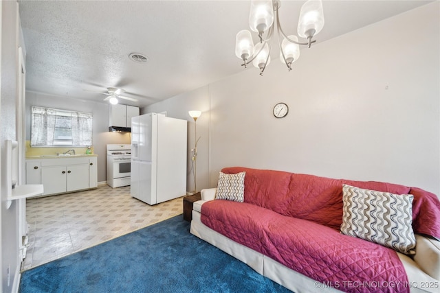 living room featuring ceiling fan with notable chandelier, sink, and a textured ceiling