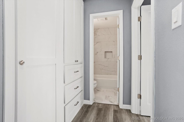 bathroom with toilet, tiled shower / bath, and hardwood / wood-style floors