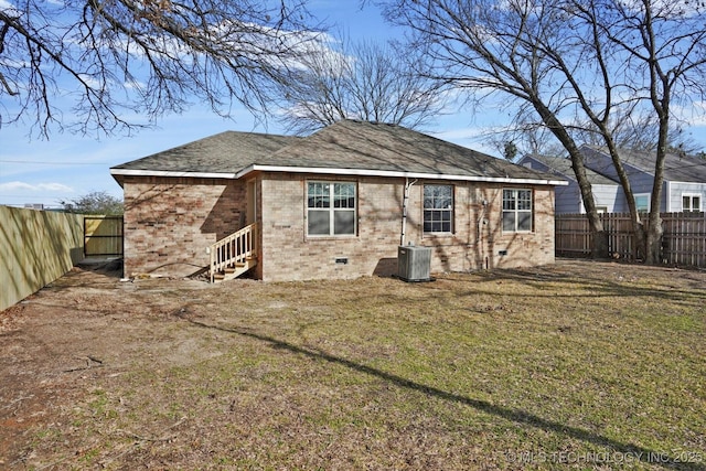 rear view of house featuring central AC unit and a yard