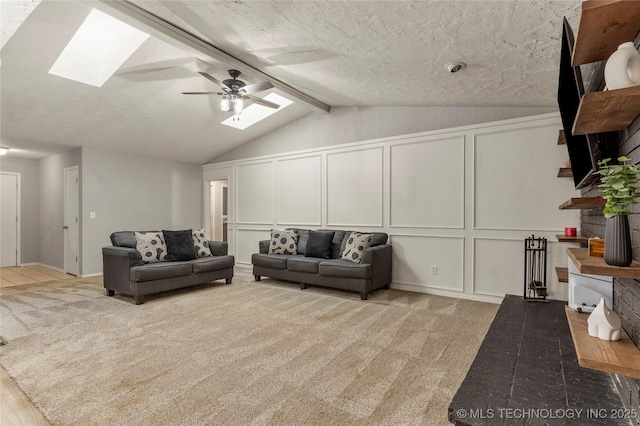 carpeted living room with ceiling fan, lofted ceiling with skylight, and a textured ceiling