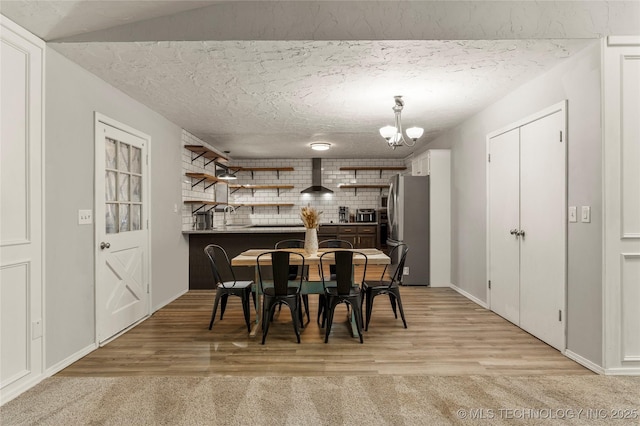 dining room featuring a notable chandelier, light hardwood / wood-style flooring, and a textured ceiling