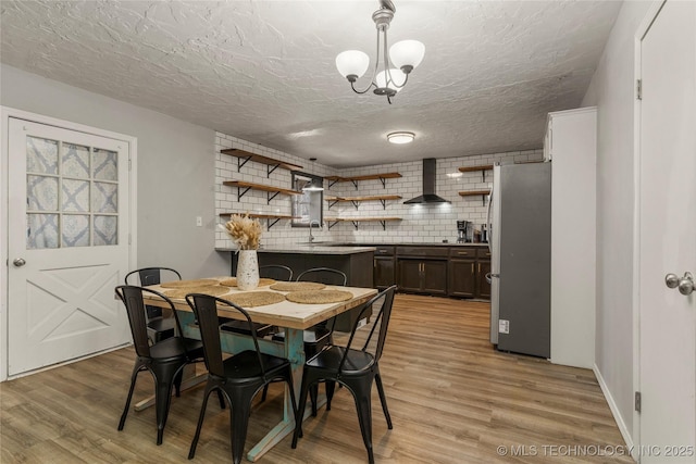 dining room featuring a chandelier, a textured ceiling, and light hardwood / wood-style floors