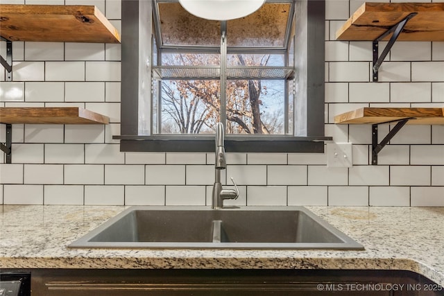 kitchen with light stone counters, sink, and decorative backsplash