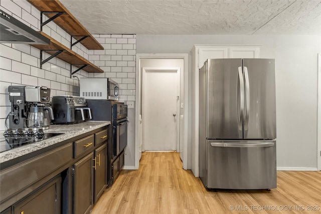 kitchen with stainless steel appliances, light hardwood / wood-style floors, decorative backsplash, and a textured ceiling